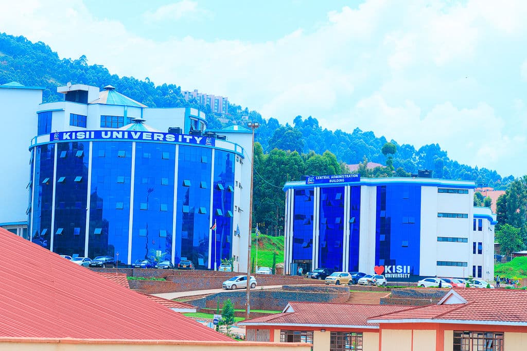 The Central Administration Building at Kisii University, its blue glass frontage carrying the university name above the Kisii highlands